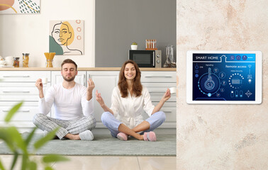 Young couple meditating in kitchen under protection of smart home security system