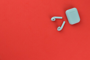 Top view of earphones over red background with copy space.