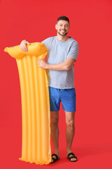 Handsome man with inflatable mattress on color background