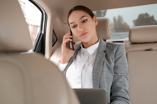 Young Businesswoman Talking By Phone On Backseat Of Car