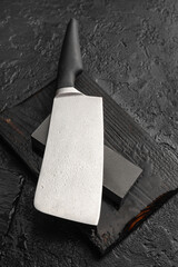 Knife with sharpening stone on dark background, closeup