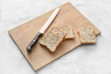 Board with knife and slices of fresh bread on light background