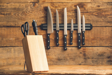 Magnetic holder and stand with set of knives on wooden background