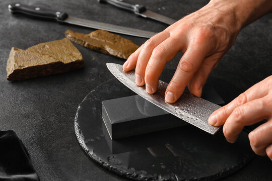 Man sharpening knife on dark background