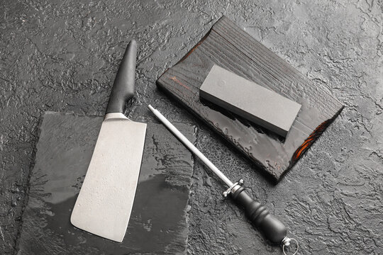 Knife with sharpener and sharpening stone on dark background