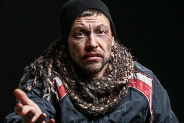 Portrait of poor homeless man on dark background
