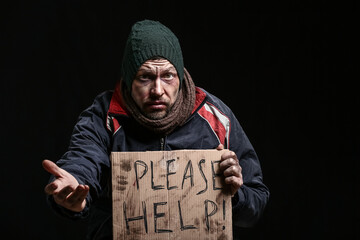 Portrait of begging homeless man on dark background