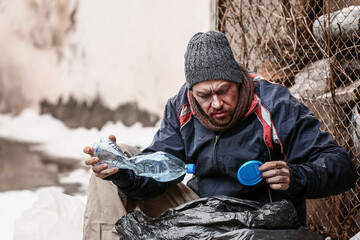 Poor homeless man with trash bag outdoors on winter day