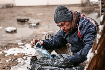 Fototapeta na wymiar Poor homeless man with trash bag outdoors on winter day