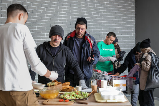 Volunteer giving food to homeless people in warming center