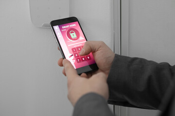 Man with mobile phone using smart home security system application, closeup