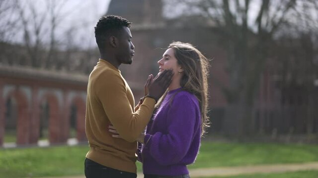 Young interracial couple hugging outside. Empathic embrace standing outside at park