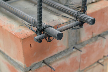 Wire bundle of metal fittings. Corrugated metal rods, flexible wire for binding. Brick wall. Selective focus.