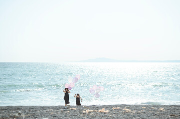 海で風船を持って遊ぶ姉妹