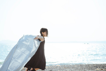 海で布を風に靡かせて遊ぶ女の子