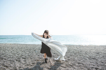 Fototapeta na wymiar 海で布と踊る女の子