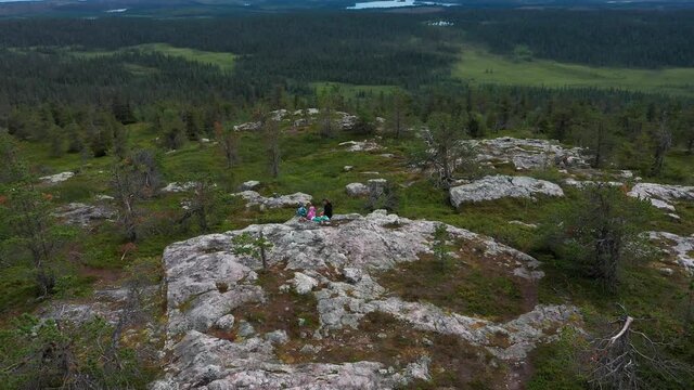 Aerial view away from mom and children on picnic on top of a arctic mountain, in Lapland - tilt up, drone shot