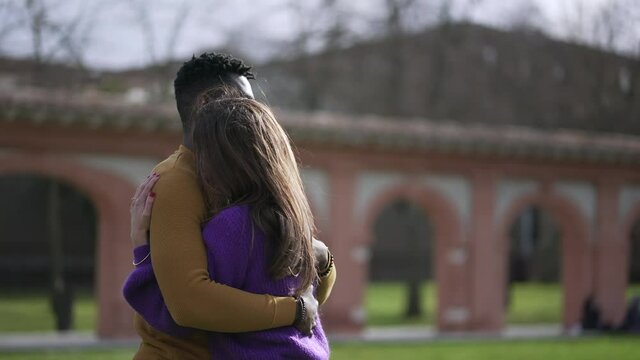 Young interracial couple hugging outside. Empathic embrace standing outside at park