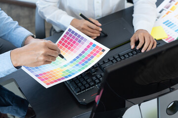 graphic designer team working on web design using color swatches editing artwork using tablet and a...