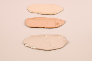  Makeup product smears on pink background. Color set of foundation, top view