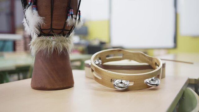 Tambourine and drum on a table in the music classroom. Zoom out.