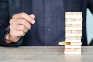 Steps of success for business or investment. Business man is arranging wood block to increase high,...