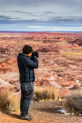 A male taking photos of the dramatic landscape of the Painted Desert in the Petrified Forest National park in Arizona.