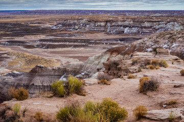 dramatic landscape photo of Blue Mesa in the Petrified Forest National Park in Arizona. Consists of flat-topped hills with rock layers in shades of blue, gray & purple.