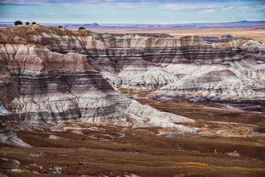 dramatic landscape photo of Blue Mesa in the Petrified Forest National Park in Arizona. Consists of flat-topped hills with rock layers in shades of blue, gray & purple.