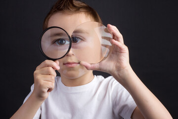 young guy in a white T-shirt looking through a magnifying glass
