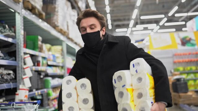 Man walking in medical mask with toilet paper shopping bags during the quarantine coronavirus COVID-19 pandemic in 2019-2021 coronavirus quarantine