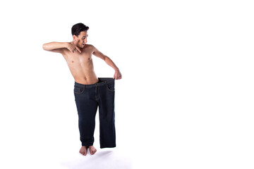 Funny young guy in big pants. Diet and weight loss. The result of fitness and training. White background. Isolate.