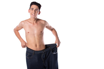Fototapeta premium Funny young guy in big pants. Diet and weight loss. The result of fitness and training. White background. Isolate.
