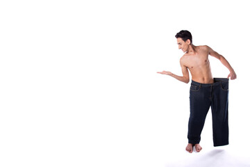 Funny young guy in big pants. Diet and weight loss. The result of fitness and training. White background. Isolate.