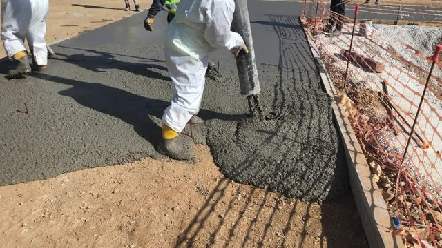 Construction workers are pouring concrete to formwork of cast in place concrete slab. Cement works. Concreting of foundation at construction site