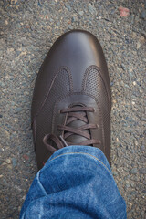 Comfortable brown leather shoes for men on asphalt road or footpath. Male footwear