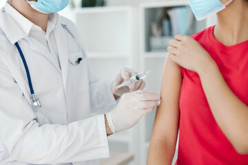 a doctor in a white coat makes an injection into the patient's arm vaccination