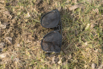 Sunglasses with black lenses and black frame shoot outside in nature in a sunny day closeup . Selective focus. High quality photo