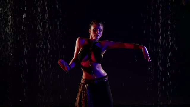 belly dance under rain, woman is dancing slowly in darkness, traditional oriental dance performance