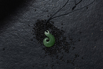 Traditional New Zealand green stone jewellery pendant on slate background. 