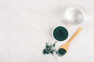 spirulina powder in a spoon on a gray table, top view, hard light, heart