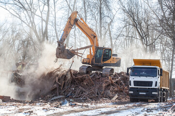 excavator loading a dump truck with debris and trash after building demolition