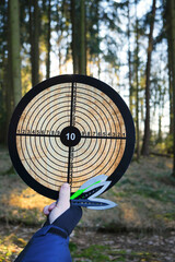 Throwing knives. Sport and hobby.Throwing knives set and target in hand on blurred forest...