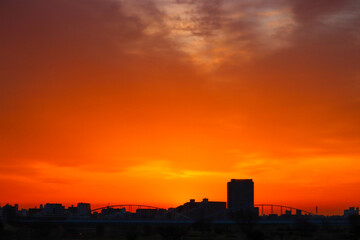 Naklejka premium Landscape of mountains and city reflected in the orange light of sunset.