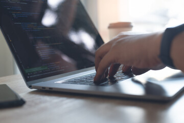 Software developer, programmer coding javascript on laptop computer, close up