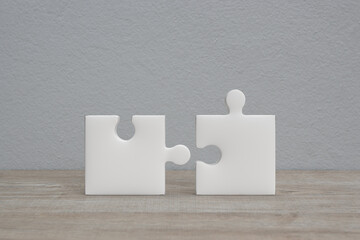 Connecting couple jigsaw puzzle on wooden table over white wall background, Business teamwork or partnership concept
