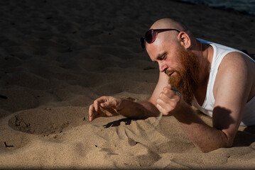 A humorous portrait of a brutal man in a T-shirt and boxers on the beach at sunset