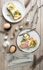 Easter breakfast with golden toasted Easter striezel or also Easter bread with butter and cheese and ham with egg and chives and basil with Easter decoration on light wooden background