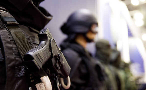 Close up soldier keeping modern gun while wearing bulletproof vest. Uniform concept.