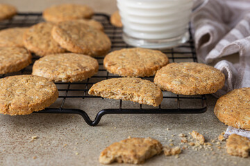 Healthy oatmeal cookies with cereals, seeds and nuts with a cup of milk on concrete background. Diet vegan cookies.